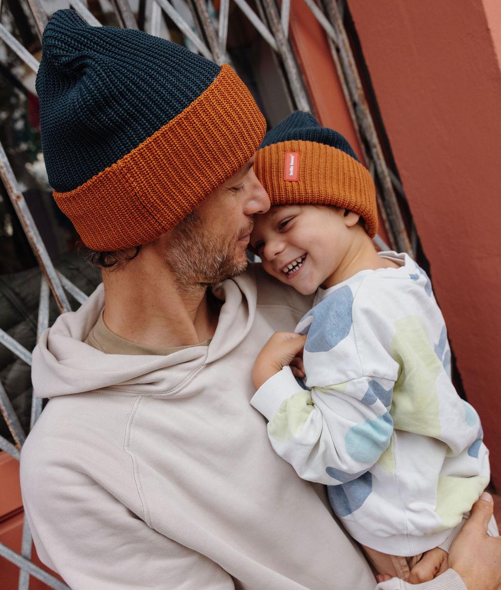 Bonnet en maille bicolore porté par un père et son fils qu'il tient dans ses bras - vue de profil - Hello Hossy