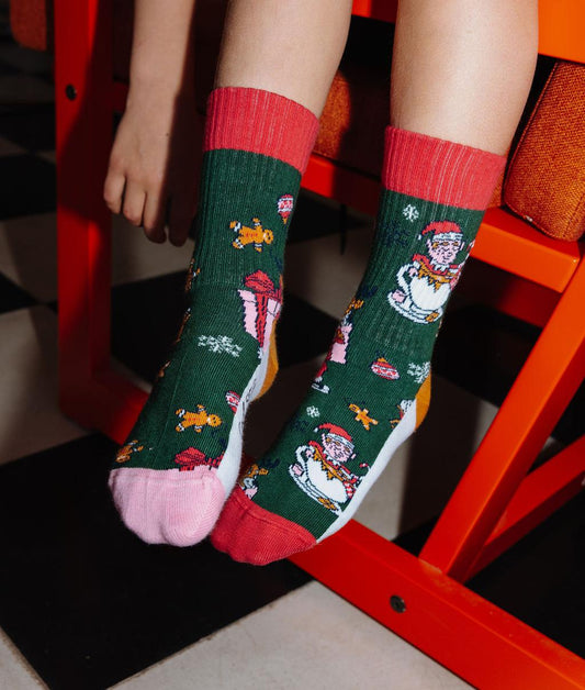 Paire de chaussettes verte motif Noël, talons et pointes colorés, portée par un enfant – photo lifestyle – Hello Hossy