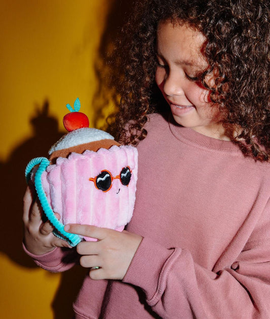 Peluche douce en forme de gâteau avec une cerise sur le dessus, Cherry Cake, tenue par un enfant – vue de 3/4 – Hello Hossy