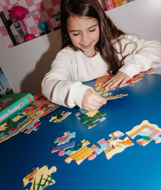 Fille qui assemble le puzzle illustré "Cherry Safari" sur une table – photo lifestyle – Hello Hossy