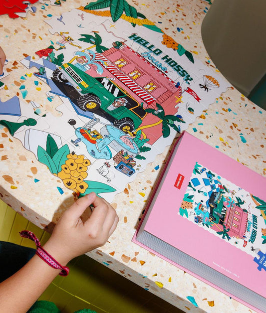Puzzle coloré "Hello Hossy House" partiellement assemblé sur une table avec la boîte à côté - vue du dessus - Hello Hossy