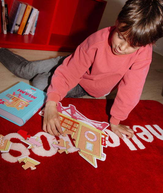 Garçon assemblant le puzzle coloré 28 pièces "Miami Plage" sur un tapis au sol – photo lifestyle – Hello Hossy